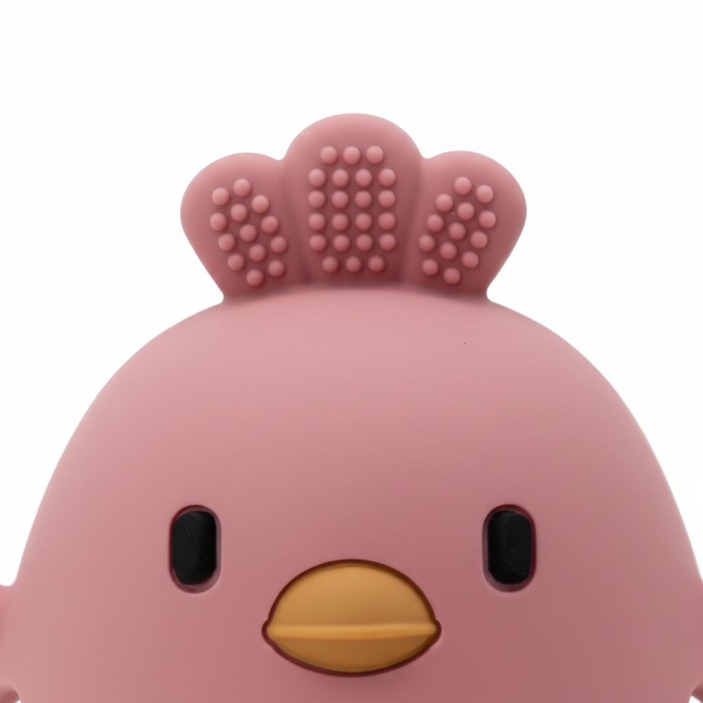 Close-up of textured crown and cartoon chick face on silicone baby teether, white background