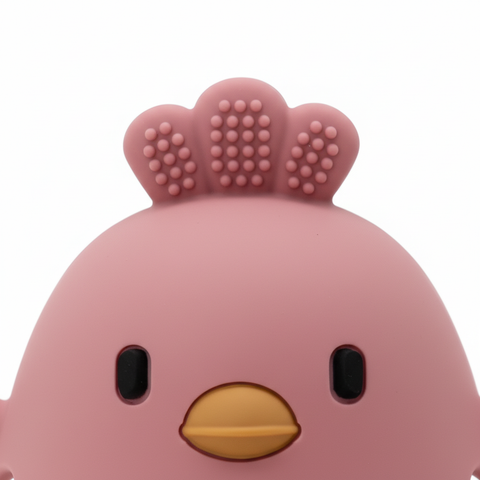 Close-up of textured crown and cartoon chick face on silicone baby teether, white background